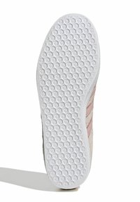 Balta kedu zole ar teksturētu rakstu, ar gaismas rozā zamša augšdaļu un horizontālām svītrām. Plakana forma ar noapaļotām malām.