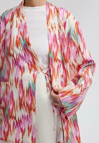 Lehký, vzorovaný kimono v odstínech růžové, oranžové a zelené; má zavazování, široké rukávy a postranní kapsy.
