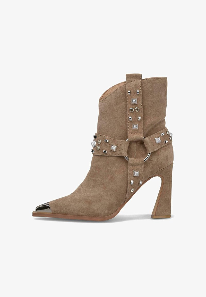 Botín de ante color caqui con punta afilada, capuchón metálico en la punta y tachuelas decorativas en la correa. Tacón de aguja y detalle de anillo en la banda.