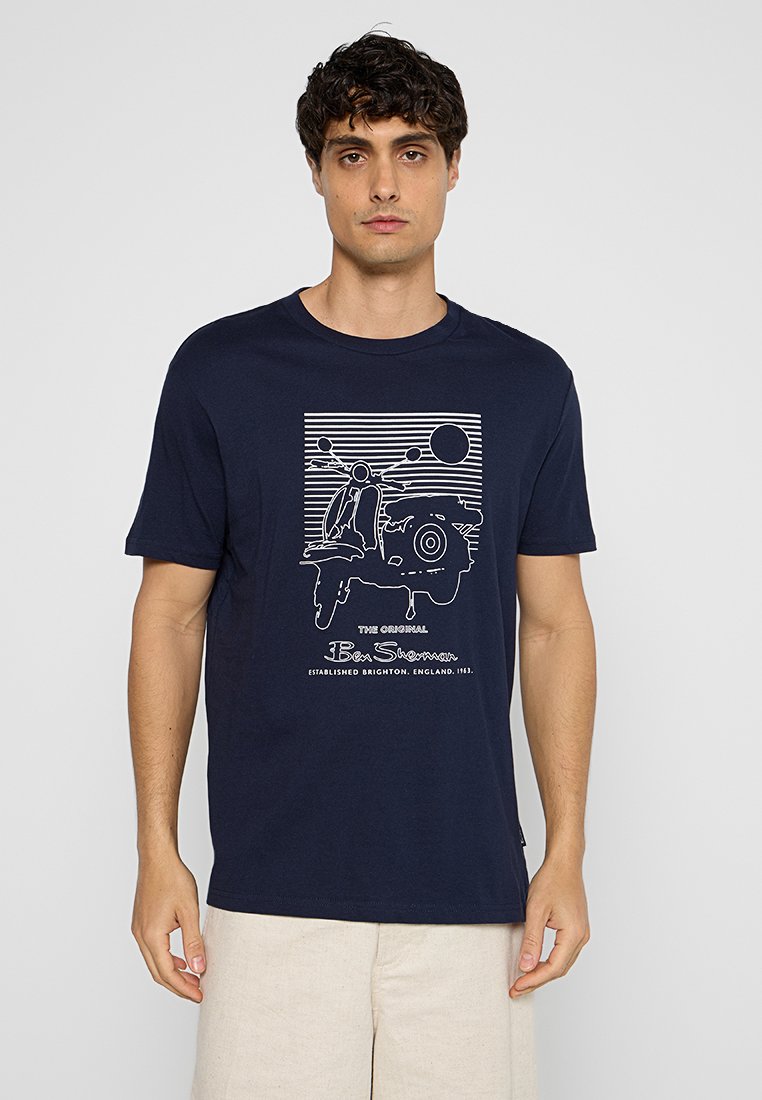 T-shirt en coton bleu marine à manches courtes, présentant un design graphique blanc d'un scooter et d'un soleil au-dessus de rayures horizontales. Coupe classique.