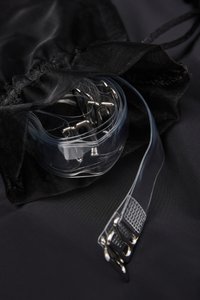 Pytlík na stažení obsahující průhledné plastové sponky a průhledné pásky na černém pozadí. Látka působí texturovaně a hladce.