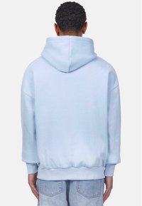 Helles blaues Kapuzensweatshirt mit lockerer Passform, gerippten Bündchen und Saum. Glatter Stofftextur, minimale Details auf der Rückseite.