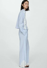 Lichtblauw en wit gestreept tweedelig outfit met een cropped top en wijde broekspijpen, voorzien van kantaccenten aan de zoom.
