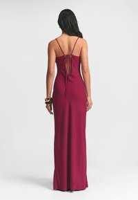 Mauve spalvos maksi suknelė su špageti petnešėlėmis, prigludusia liemene ir atvira nugara, užsegta nėriniu. Sklandus tekstūra su minimalizmo dizainu.