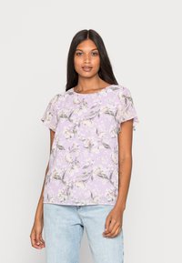 Blusa floral roxa com mangas curtas, apresentando um decote redondo e um corte solto. Padrão floral em tons de rosa e verde.