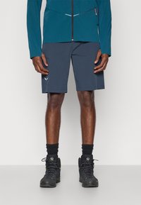 Ανδρικές ναυτικές σορτς φτιαγμένες από ελαφρύ ύφασμα, με διακριτικό λογότυπο, σε κομψό σχέδιο και πρακτική εφαρμογή. Μαύρα υποδήματα με ορατή υφή.