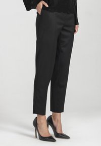 Czarne dopasowane spodnie z prostą nogawką, gładką fakturą i czystymi liniami. Połączone z czarnymi szpilkami, eksponując eleganckie obuwie.