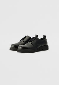Zwarte leren veterschoenen met een ronde neus, een gladde oppervlakte en een dikke, platte zool. Het design is eenvoudig met minimale details en bevat een trekstrip.