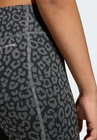 Čierne legíny s šedým leopardím vzorom, vyrobené z pružného materiálu. Obsahujú viditeľné ploché švy a označenie "CLIMACOOL".