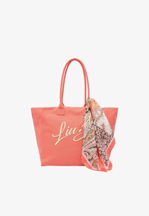 Borsa a tracolla corallo con manici in tessuto, logo bianco in corsivo sul davanti e foulard di seta con fantasia drappeggiato su un lato.