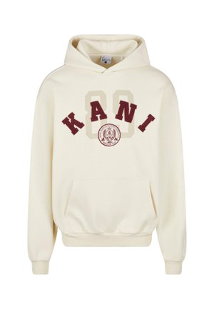 Kremkrāsas kapučš jaka ar vārdu "KANI" bordo un smilškrāsā, ar apļa emblēmu virs kabatas un ribota apakšmala.