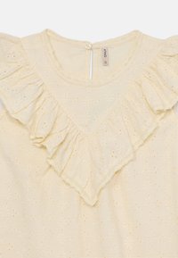 Lys gul bluse med volangede halslinje, blomsterbroderi og små utskjæringer. Lukkes bak med en enkelt knapp. Myk, strukturert stoff.