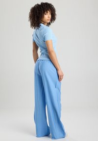 Light blue ribbed short-sleeve top paired with loose, flowy light blue pants. The fabric appears soft and textured, with a relaxed fit.