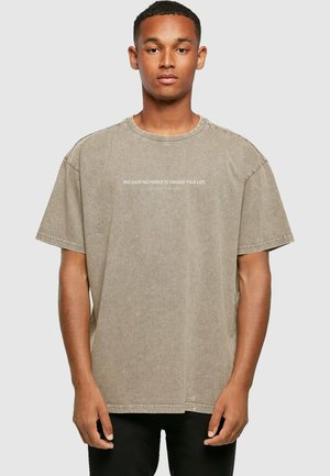 Khaki oversized T-shirt lavet af struktureret bomuld, med rund halsudskæring og trykt tekst på fronten. Korte ærmer og en afslappet pasform.