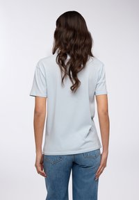 T-shirt azzurro chiaro a maniche corte con una vestibilità comoda, realizzato in tessuto morbido; indossato con jeans di denim blu a vita alta.