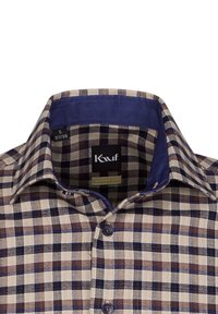 Camicia a quadri in beige, blu e marrone. Presenta un colletto punta con un interno blu uniforme. Chiusura frontale con bottoni scuri e etichetta del marchio all'interno.