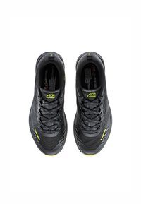 Black athletic shoes with a textured upper, contrasting lime green accents, and a lace closure. Features a streamlined design and lightweight profile.