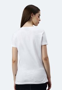 Weißes Baumwoll-T-Shirt mit kurzen Ärmeln, Rundhalsausschnitt und gerader Passform. Die Rückansicht zeigt ein dezentes Logodetail im Nackenbereich.