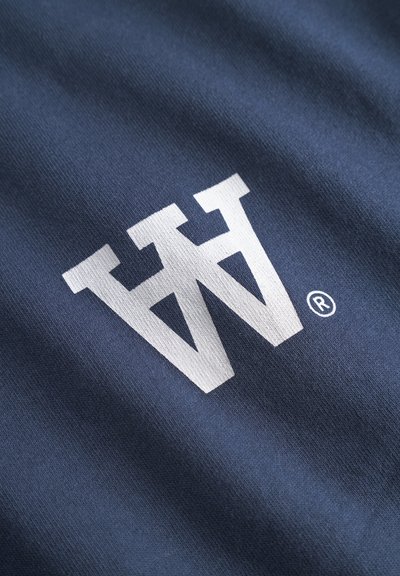 Tissu bleu marine avec une texture lisse, arborant un logo "W" stylisé en blanc et un symbole de marque déposée.