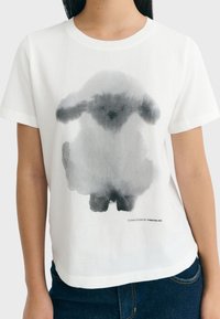 Weißes Baumwoll-T-Shirt mit einem grauen Aquarell-Hasenmotiv. Rundhalsausschnitt, kurze Ärmel, lockere Passform mit abgerundetem Saum. Markenetikett am unteren Rand.
