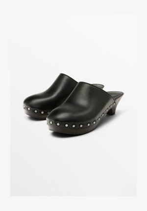 Black leather clogs with a smooth finish, featuring silver studs along the side, and a low wooden heel. Closed back design.