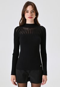 Maglione nero a coste con maniche lunghe e collo alto. Presenta pannelli trasparenti sulle spalle e un piccolo logo sull'orlo.