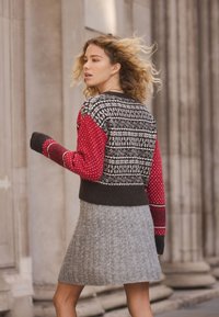 Neulepaita, jossa punaiset ja mustat kuviolliset hihat, villasekoitemateriaali. Yhdistetty harmaaseen resorihameeseen. Mukava ja teksturoitu muotoilu.