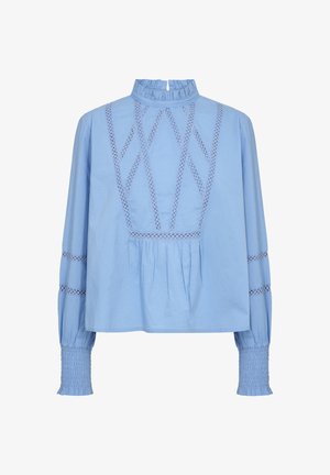 Svijetloplava bluzica s visokim nabranim ovratnikom, složenim vezenjem u dijamantnom uzorku i dugim rukavima koji imaju smotane manšete i horizontalne izreze.