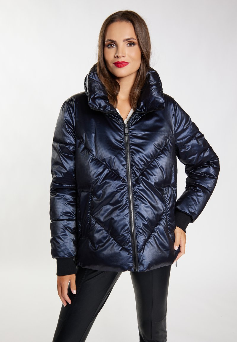 Giacca puffer blu navy con colletto alto, chiusura a zip frontale, motivo a zig-zag e polsini rigati neri. Texture liscia e lucida.