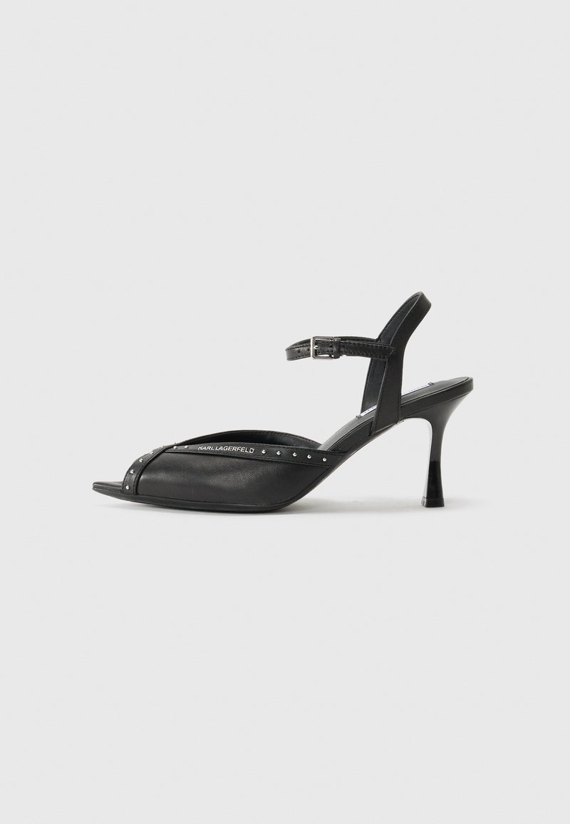 Zwarte hoge hak sandalen met een puntige neus, enkelbandje en studs. Gemaakt van leer met een gladde textuur en een slank ontwerp.