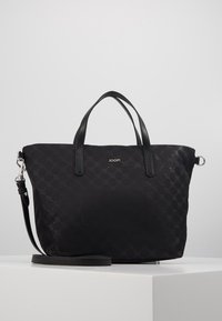Schwarze Tasche mit strukturiertem Muster, ausgestattet mit zwei oberen Handgriffen und einem abnehmbaren Schultergurt. Mit silberner Hardware und einem Logo-Detail.