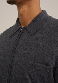 Kragenhemd in Anthrazitgrau mit einem halben Reißverschluss, weichem Material und einer Brusttasche für praktische Details.