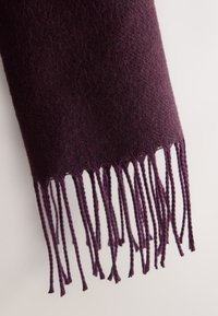 Violets vilnas šalle ar mīkstu tekstūru, kurai ir smalki mezgloti bārkstis. Audums izstaro smalku, vienmērīgu pinumu.