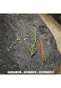 Green rosemary sprig, green and beige cardamom seeds, brown cedar wood fragment on a textured dark stone surface.