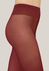 Bordeauxfarbene, transparente Strumpfhose mit glatter Textur und breitem Bund, entworfen für eine eng anliegende Passform. Reichweite bis zur Mitte des Oberschenkels, leichtes Material.