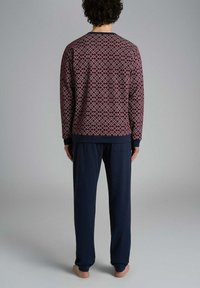 Felpa a motivi bordeaux con design geometrico, abbinata a pantaloni da pigiama blu navy uniti. Tessuto morbido, maniche lunghe, vestibilità ampia.