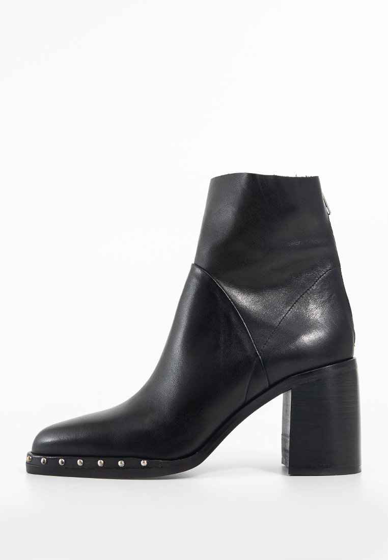 Schwarze Lederstiefelette mit spitzer Zehenpartie, robustem Blockabsatz und dekorativen silbernen Nieten entlang der Sohle. Glatte Struktur mit minimalistischem Design.