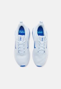 Baskets de sport en maille blanche avec un swoosh Nike bleu, des accents bleus et un col rembourré ; les lacets et les semelles rembourrées améliorent le confort.