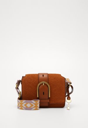 Petit sac bandoulière marron texturé avec une grande boucle dorée, une bandoulière réglable à motifs et un porte-clé décoratif doré suspendu.