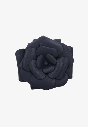 Dunkel marineblaues Leder-Accessoire in Blumenform mit geschichteten, abgerundeten Blütenblättern, die spiralartig angeordnet sind.