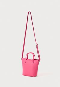 Petit sac à main rose en matériau synthétique. Doté de courtes poignées supérieures et d'une bandoulière longue amovible. Texture lisse, design minimaliste.