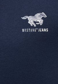 Navyblaue Baumwoll-T-Shirt mit einer Grafik eines weißen Pferdes und dem Text "MUSTANG JEANS" in fetter Schrift unter dem Bild.