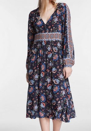 Robe à manches longues bleu marine à motif floral avec col en V, détails à la taille et bordure à motifs sur les manches et la taille, portée par une personne debout.