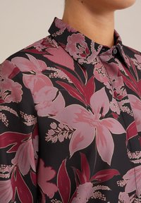 Blusa con colletto in tessuto leggero nero, caratterizzata da una grande stampa floreale rosa e bordeaux, dalla texture morbida e con chiusura a bottoni.