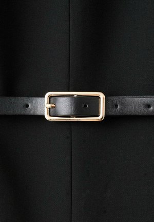 Black leather belt with a gold rectangular buckle fastened around black textured fabric background.