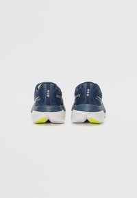 Zapatillas de running en color navy con parte superior de malla, acentos en lima contrastantes, suela acolchada y talón texturizado. Diseño ligero con forma aerodinámica.