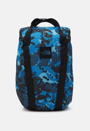 Sac à dos à motif camouflage bleu et noir avec des bretelles noires et un patch logo « The North Face » centré à l’avant.