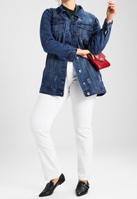 Jeansjacka med knäppning framtill, två bröstfickor och en något oversized passform, matchad med vita byxor och svarta lägenheter. Röd handväska som accent.