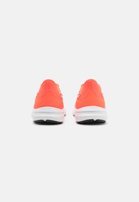 Chaussures de sport orange vif avec une tige en mesh et une semelle blanche rembourrée. Design à talon arrondi avec une traction noire sur la semelle extérieure.