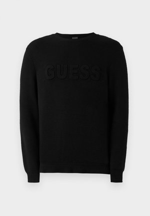 Maglione nero realizzato in morbido tessuto a maglia. Presenta un logo "GUESS" in rilievo sul davanti, colletto rotondo e polsini e orlo a coste. Design semplice.